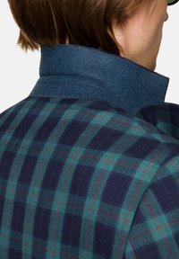 Koszula w kratę w kolorach zielonym, granatowym i czerwonym, z ciemnoniebieskim filcowym kołnierzykiem i teksturowanym materiałem, ukazana z tyłu.