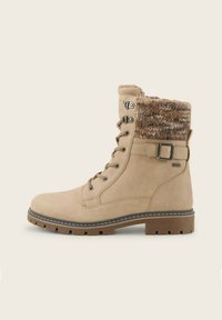 Botines beige con un puño de punto texturizado, ojales metálicos y una hebilla cuadrada; cuentan con una suela tipo taco para tracción y estabilidad.