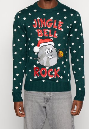 Pull vert foncé à pois blancs, roche souriante portant un chapeau de Père Noël tenant une cloche, avec le texte rouge "JINGLE BELL ROCK".