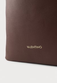 Brown textured leather bag with a gold "Valentino" logo on the front. Smooth finish, rectangular shape, minimalistic design.