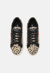 Levi's sneakers i beige lerret med svart leopardmønster, med svarte lisser og detaljer, hvit såle og logomerke på tungen.
