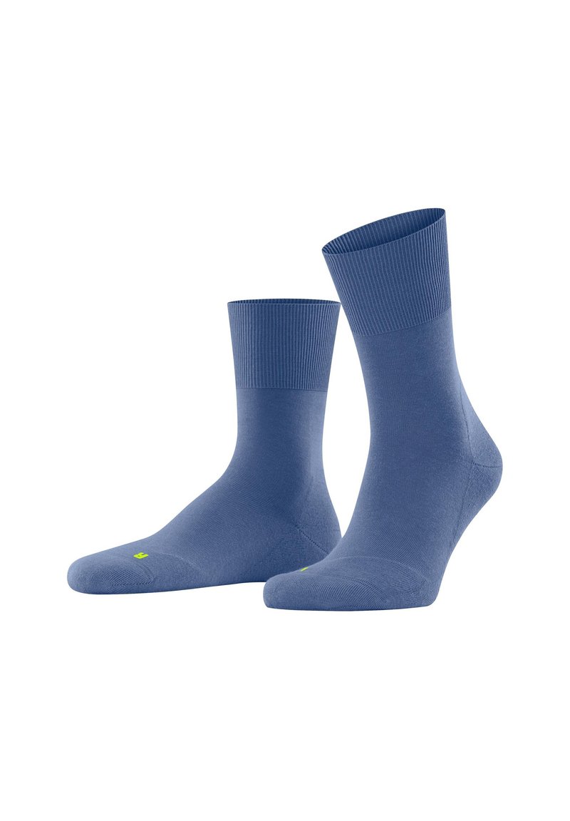 Chaussettes bleues en tissu lisse, avec un bord-côte et un orteil renforcé. Étiquetées d'un petit logo jaune sur la semelle.