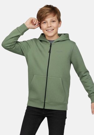 Groene hoodie met rits, gemaakt van zacht materiaal. Voorzien van een capuchon, steekzakken aan de voorkant en een subtiel logo. Gecombineerd met zwarte spijkerbroek.
