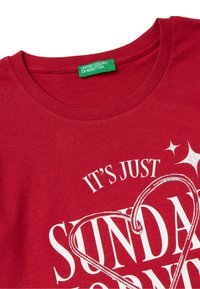 Rode katoenen T-shirt met ronde halslijn, voorzien van witte bedrukte tekst en sprankelende accenten, ontworpen door United Colors of Benetton.