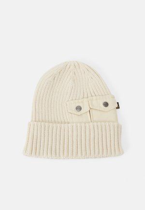 Cream knitted beanie with ribbed texture and a folded cuff. Features two external buttoned fabric pockets on the side.