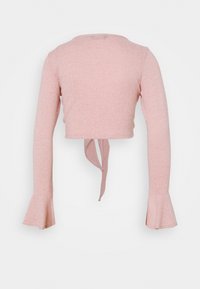 Rosa långärmad croppad topp med utställda ärmslut och knytning i ryggen, visad bakifrån.