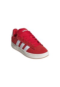 Rote Wildleder-Sneaker mit weißen drei-Streifen-Design, Gummisohle und gepolstertem Kragen. Die Schnürsenkel sind ebenfalls rot, mit einem Logo auf der Zunge.