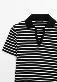 Chemise à manches courtes à rayures horizontales noires et blanches avec un col noir et une ouverture en V.