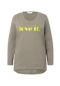 Pitkähihaista oliivinvihreää t-paitaa pehmeästä puuvillasta, jossa on keltainen printti tekstillä "love it." keskellä, pyöreä kaula-aukko ja kaareva helma.