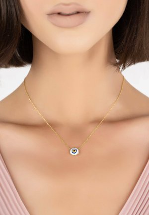 Goldkette mit einem runden Anhänger, der ein blaues und gelbes Augendesign zeigt, vor einem hellen Hintergrund.