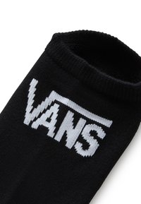 Schwarze Socke mit einem weißen "VANS"-Logo, das in den Stoff eingestrickt ist. Der obere Rand ist gerippt und die Textur wirkt weich und dehnbar.