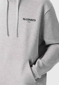 Szürke kapucnis pulóver puha anyagból, elülső zsebbel. A mellkason fekete "ALLSAINTS" és "LONDON" felirat található.