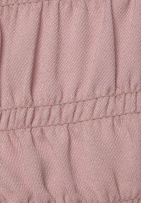 Tissu rose texturé avec deux rangées parallèles de couture formant des plis froncés à travers le matériau.