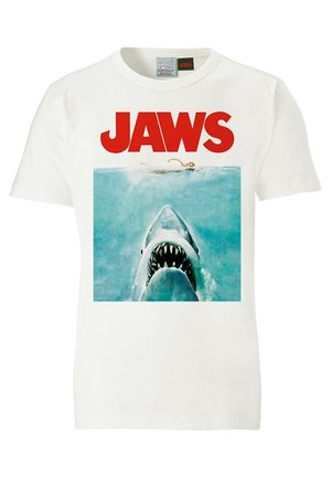 Wit T-shirt met JAWS in rode tekst boven een afbeelding van een zwemmer en een grote haai die met open kaken omhoog zwemt.