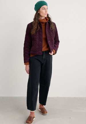 Livet quiltet lilla jakke, kastanjefarvet sweater, sorte straight-leg jeans, brune klipklapper og grøn strikket hue. Teksturerede materialer og kontrastfarver.