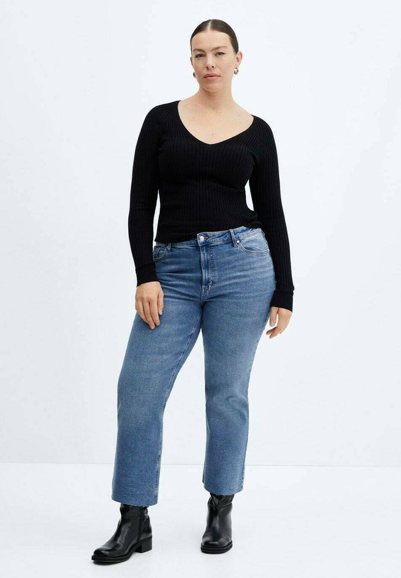 Zwarte geribbelde lange mouw top gecombineerd met lichtblauwe rechte jeans en zwarte enkellaarsjes. Eenvoudig, aangesloten ontwerp met een v-hals.