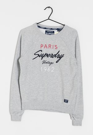 Lichtgrijs sweatshirt met lange mouwen en de tekst "Paris Superdry Vintage 1962" op de voorkant, hangend aan een zwarte hanger tegen een witte achtergrond.
