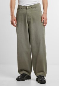 Wide-leg, olive green cotton pants with a smooth texture, featuring front pockets and a button closure, paired with black footwear.