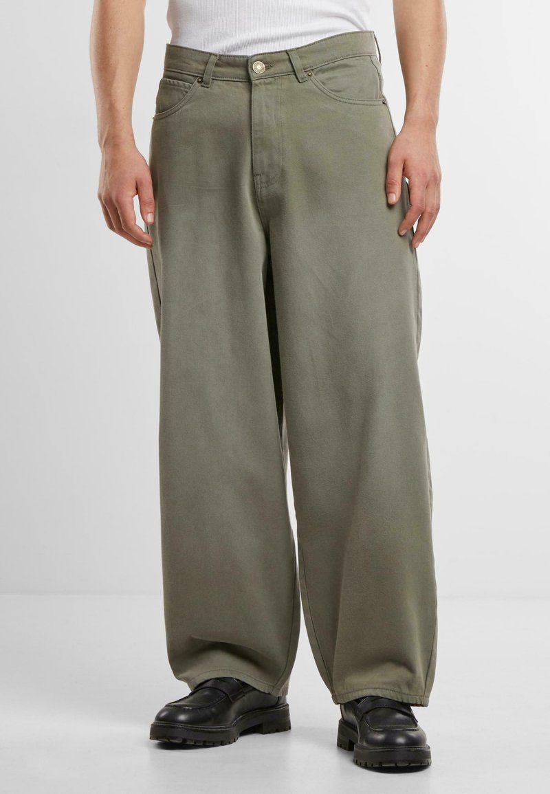 Wide-leg, olive green cotton pants with a smooth texture, featuring front pockets and a button closure, paired with black footwear.
