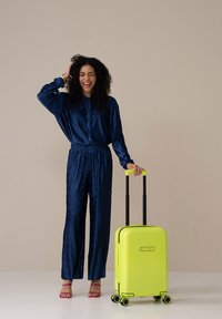 Harde koffer in fel neon geel met gestructureerde verticale strepen. Voorzien van vier zwarte wielen en een uitschuifbare handgreep.