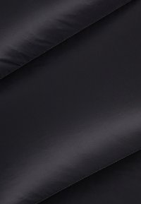 Tissu noir avec une texture lisse et légèrement brillante ; présente un motif diagonal subtil ; les bords sont ornés de coutures contrastantes.