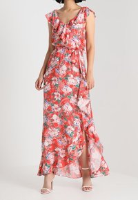 Květinové maxi šaty v korálové barvě s řasenými rukávy a vázačkou v pase. Mají rozparek na noze, průhlednou látku a vrstvený design živůtku.