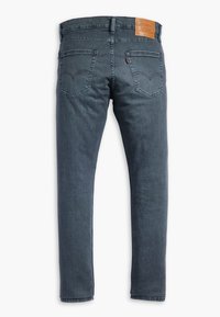 Mörka denimjeans med rak passform, med två bakfickor och en l äderlapp vid midjan. Distinkt stående sömmar.
