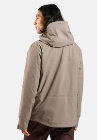 Beige wasserdichte Jacke mit Kapuze, die eine glatte Textur, verstellbare Bündchen und einen geraden Schnitt aufweist. Die Rückansicht zeigt eine Nahtdetails.