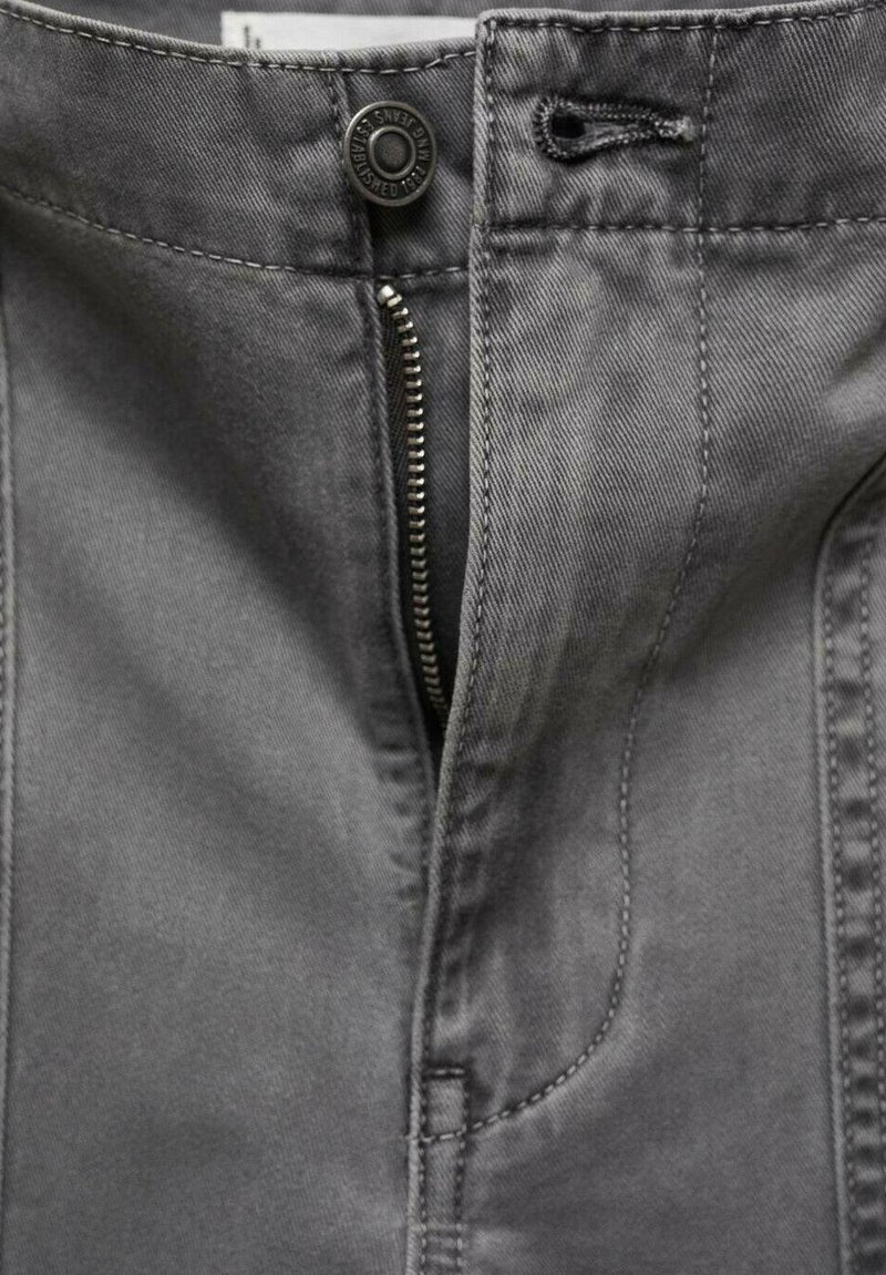 Szare dżinsowe spodnie z zamkiem błyskawicznym z przodu i guzikem, z widocznymi szwami i gładką teksturą, podkreślającymi praktyczne detale designu.