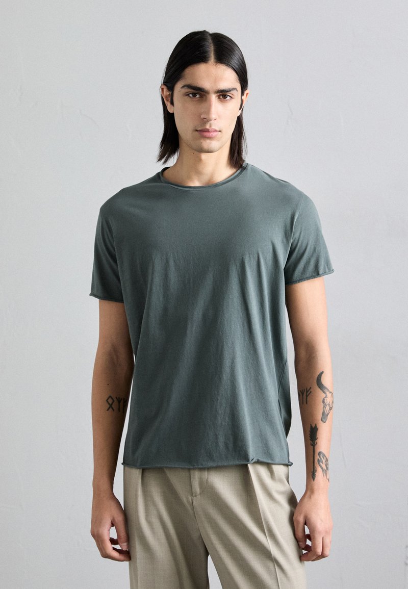 Dark green cotton crewneck t-shirt with short sleeves, featuring a relaxed fit. Smooth texture, straight hem, and subtle stitching details.