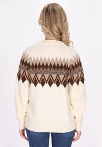 Maglione color crema con un motivo a rombi marrone sulla parte superiore della schiena, dotato di maniche raglan e collo e polsini a costine.