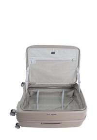 Hard-shell beige suitcase with smooth texture, zip closure, organizational straps, and patterned interior lining. Features four spinner wheels.