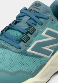 Hele sinine spordijalats tekstuurse võrkpealsega, kontrastsete tumelindiga ja suure valge "N" logoga küljel. Kerge tald.