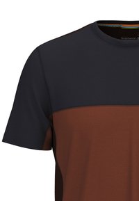 Camisa de manga corta que presenta una sección superior de color azul marino oscuro y un panel inferior de color óxido, hecha de un tejido transpirable con una textura suave.