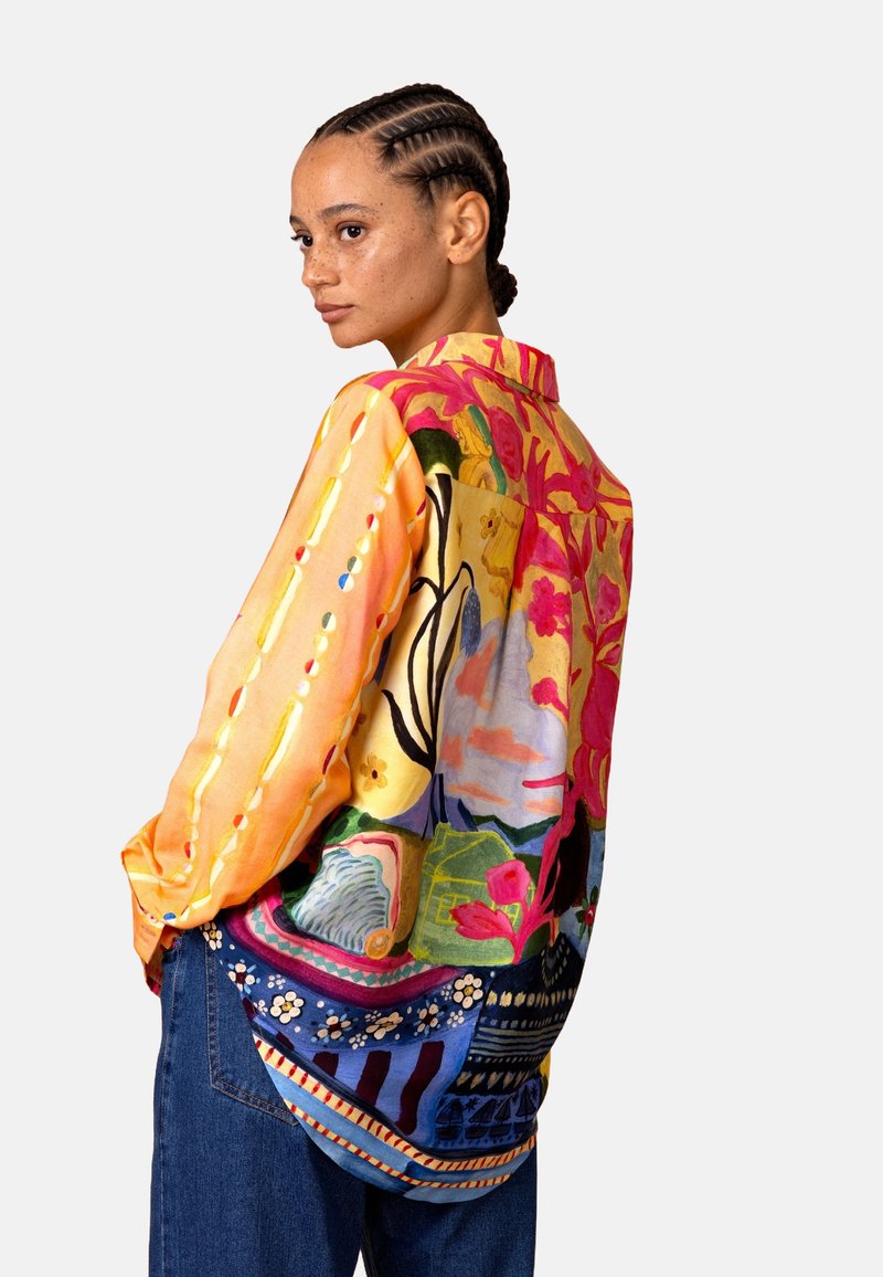 Kleurrijk, oversized zijden overhemd met een levendig bloemen- en abstract ontwerp in tinten geel, roze en blauw met gedetailleerde patronen.