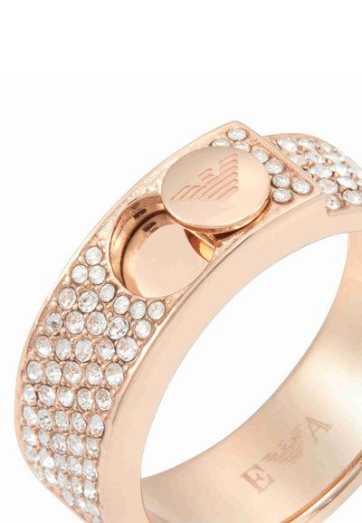 Roséguld ring som har en slät ring med klara kristaller och en cirkulär detalj med en graverad logotyp.