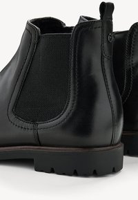 Bottines Chelsea en cuir noir avec panneaux latéraux en élasthanne, accents en tissu texturé, semelle extérieure robuste à crans et une finition lisse et polie.