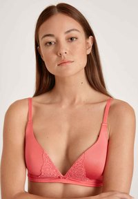 Coral triangle bra featuring lace accents, adjustable straps, and a smooth fabric texture. Designed for comfort with a feminine aesthetic.