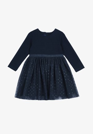 Vestido azul marino con mangas largas, cuerpo texturizado y falda de tul en capas adornada con pequeños lunares dispersos. Detalle de cinturilla de satén.