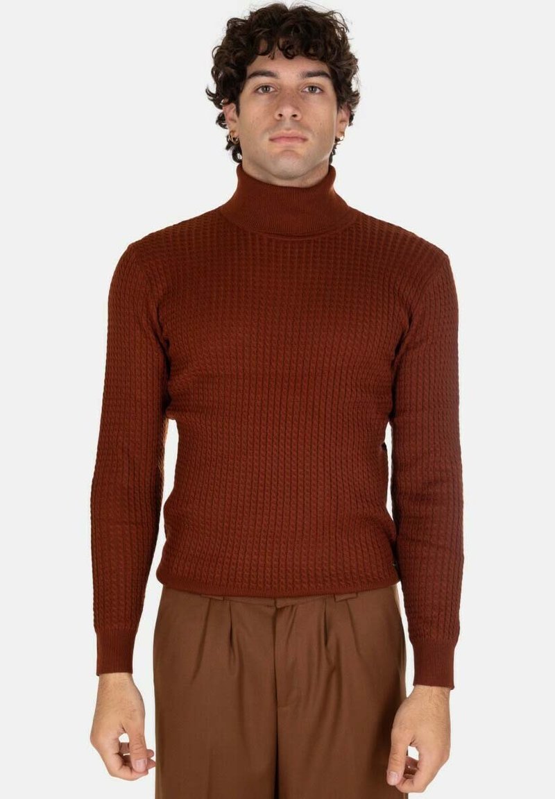 Maglione a collo alto color ruggine con texture a coste, stile aderente e maniche lunghe, abbinato a pantaloni marroni.