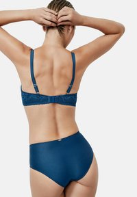 Marineblauwe lingerie set met een kanten bralette met verstelbare banden en een gladde hoog-gesneden onderkant. Kenmerken zijn onder andere een handmatige sluiting.