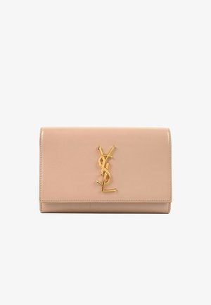 Beżowa skórzana kopertówka z złotym logo YSL na środku przedniej klapy, prostokątny kształt i przeszywane krawędzie.