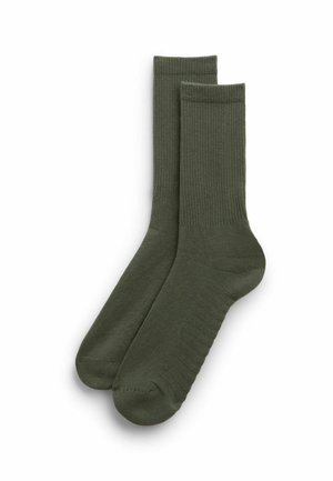 Par af olivengrønne crew-strømper med ribbet tekstur på benene og glat fodområde, lagt fladt på en hvid baggrund.