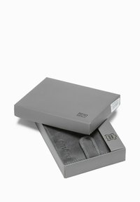 Cartera gris segura RFID partially dentro de una caja gris con "gmbre" grabado en la cartera y una etiqueta de cuero genuino visible.