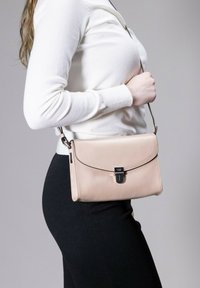 Helle rosa Lederhandtasche mit Klappenverschluss, silberner Beschläge und abnehmbarem Trageriemen, die eine glatte Textur und ein minimalistisches Design zeigt.