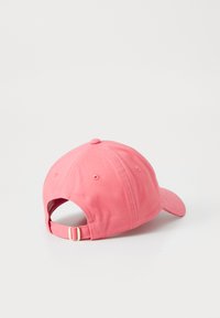 Pink cotton baseball cap with a curved brim, adjustable strap at the back, and button detail on top. Soft texture and no visible patterns.