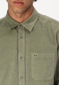 Groene corduroy overhemd met een knoopsluiting, spitse kraag, een voorzak met een logo patch en een gestructureerde ribbelstof.