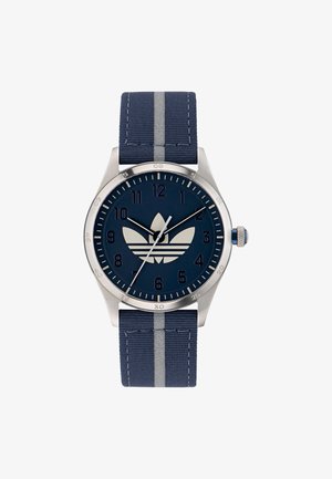 Mornarska ura s ohišjem iz nerjavnega jekla, temno modrim številčnikom, belimi oznakami ur in tekstilnim trakom z sivo črto.