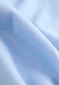 Tissu tricoté bleu clair avec une texture lisse, présentant des points fins et réguliers ainsi qu'un tombé souple.