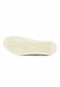 Suola di sneakers bianca con un motivo zigzag testurizzato, un logo circolare sul tallone e un bordo liscio e curvo.